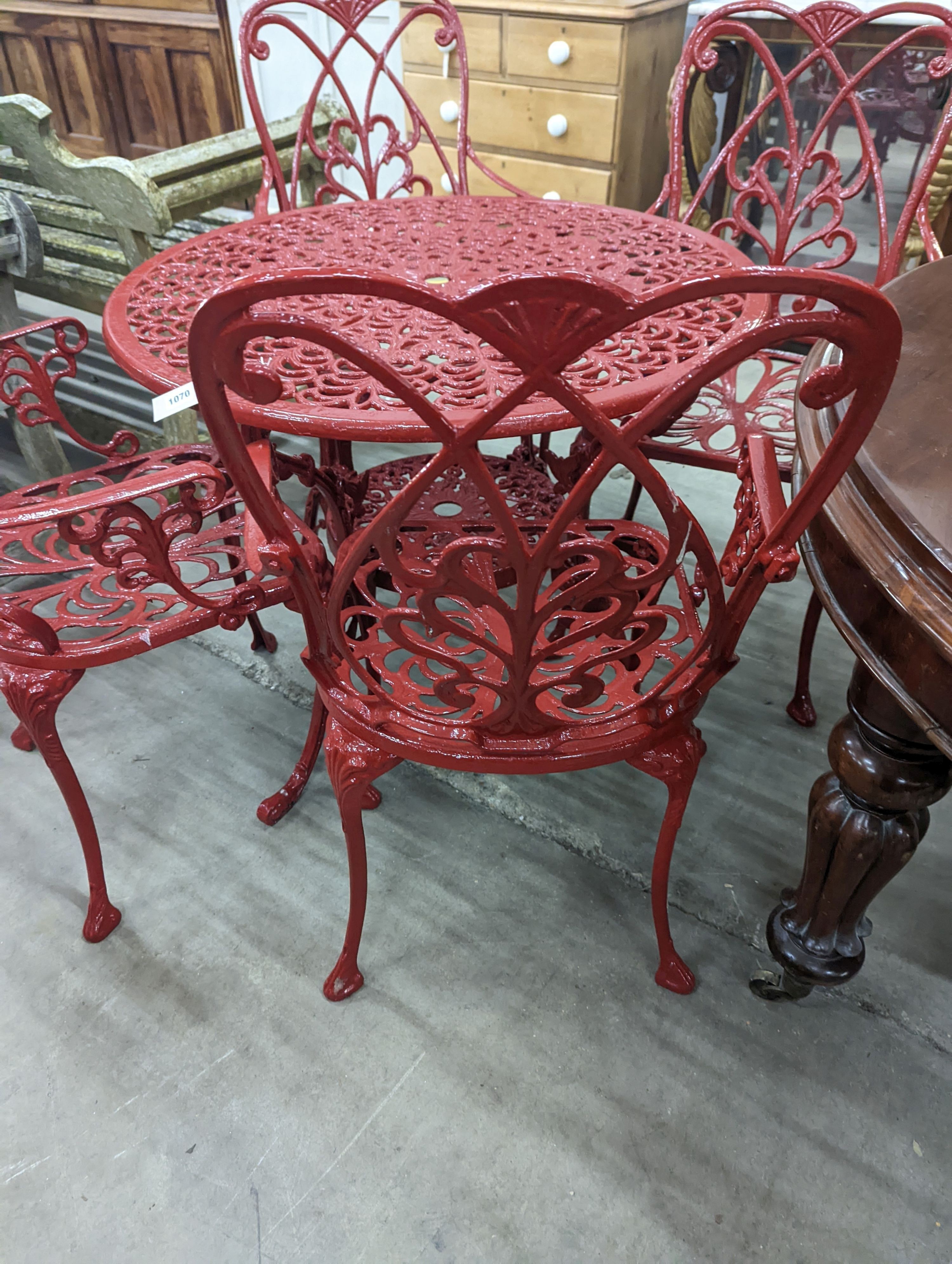 A circular red painted aluminium garden table, diameter 86cm, height 67cm together with four matching chairs